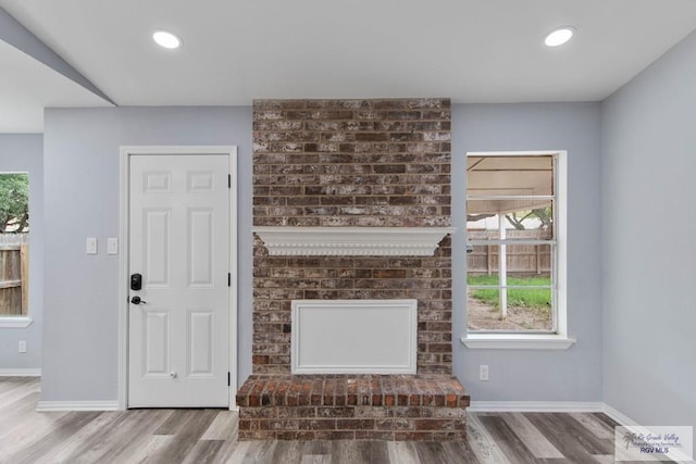 unfurnished living room featuring hardwood / wood-style flooring and a brick fireplace