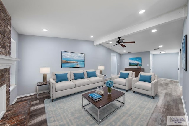 living room with ceiling fan, wood-type flooring, a brick fireplace, and vaulted ceiling with beams