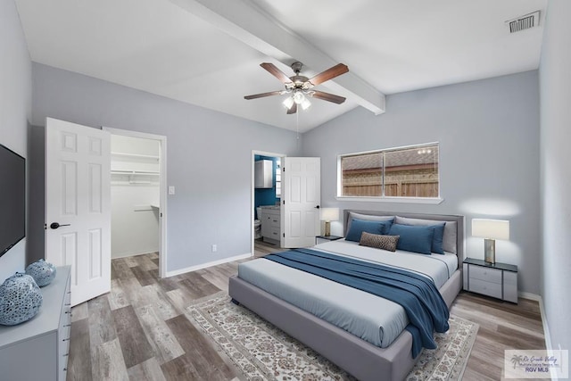 bedroom with vaulted ceiling with beams, a walk in closet, wood-type flooring, a closet, and ceiling fan