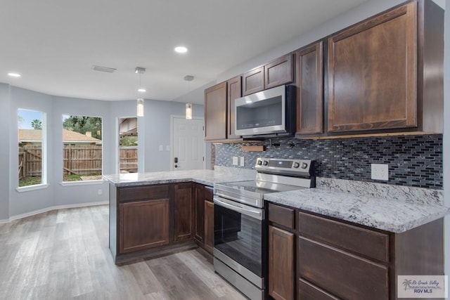 1722 High St, Harlingen, TX 78550 - kitchen with light wood-style floors, tasteful backsplash, a peninsula, appliances with stainless steel finishes, and light stone counters