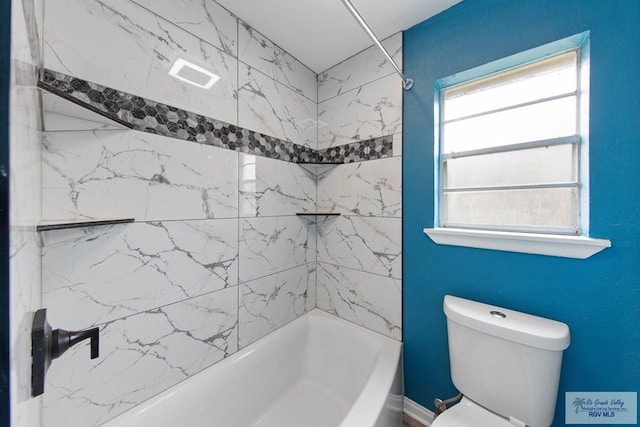 bathroom with tiled shower / bath combo and toilet