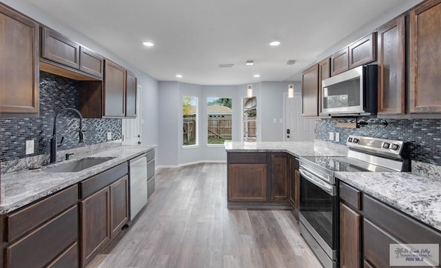 kitchen with appliances with stainless steel finishes, pendant lighting, sink, dark brown cabinetry, and kitchen peninsula