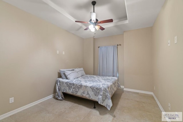 bedroom with ceiling fan and a tray ceiling