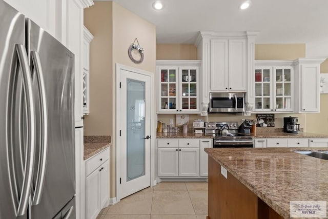 kitchen with white cabinetry, light tile patterned floors, light stone countertops, and appliances with stainless steel finishes