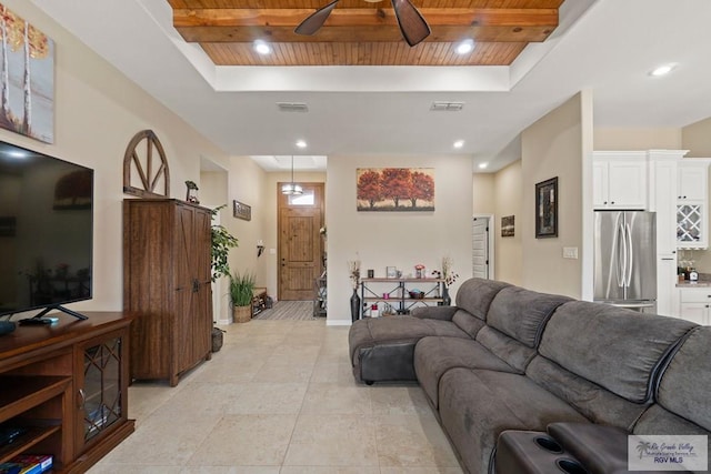 tiled living room featuring wood ceiling, ceiling fan, and a raised ceiling