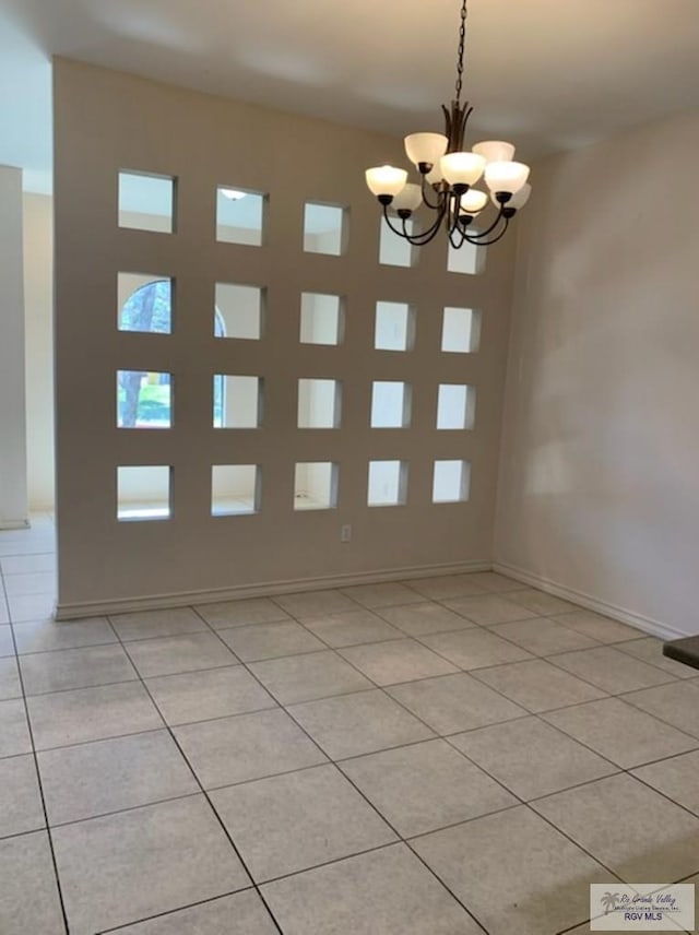 tiled empty room with an inviting chandelier