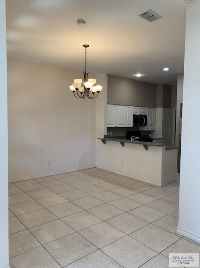 kitchen featuring light tile patterned floors, white cabinetry, hanging light fixtures, a notable chandelier, and kitchen peninsula