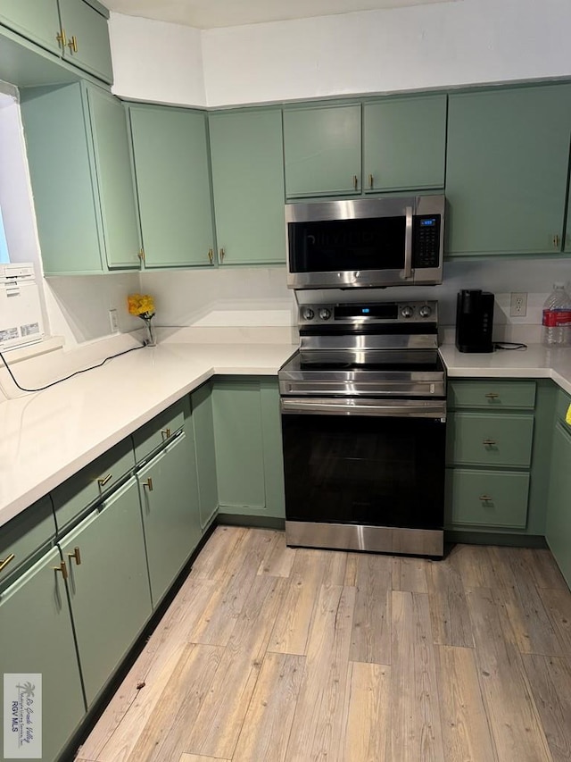 kitchen with appliances with stainless steel finishes, light hardwood / wood-style floors, and green cabinets