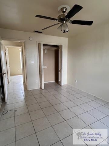 unfurnished bedroom with ceiling fan, a closet, and light tile patterned floors