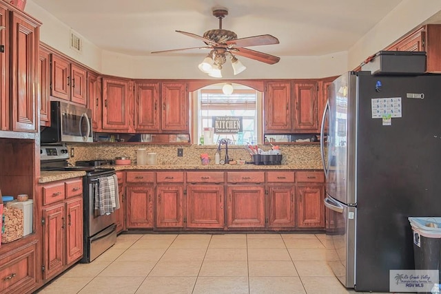 kitchen with light tile patterned floors, light stone counters, stainless steel appliances, a sink, and visible vents