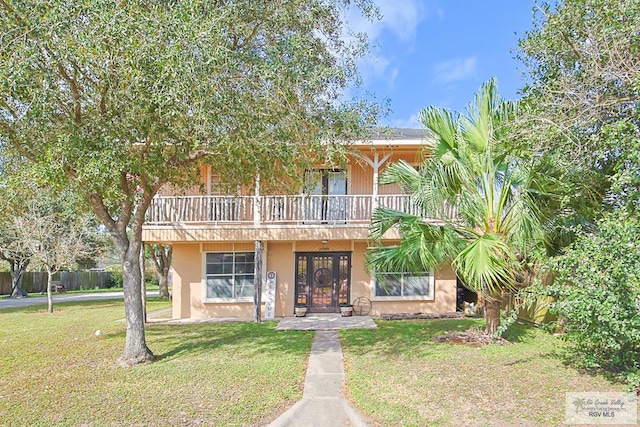 view of front of property featuring a balcony, stucco siding, and a front yard