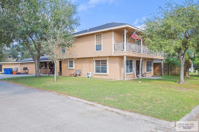 exterior space with a balcony, stucco siding, fence, and a yard