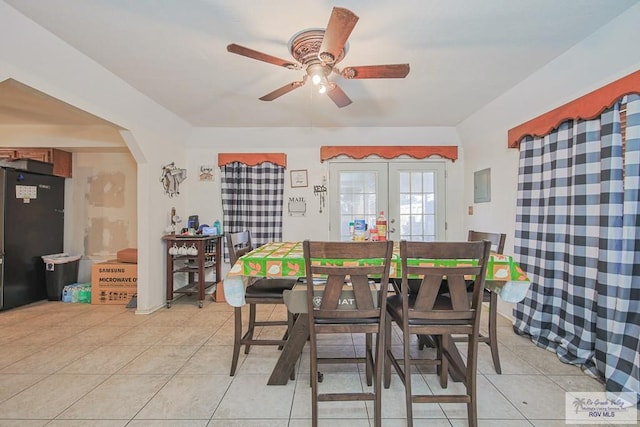 dining space featuring a ceiling fan, arched walkways, french doors, and light tile patterned flooring