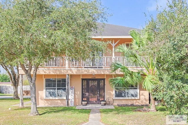 view of front facade featuring stucco siding, a front yard, and french doors