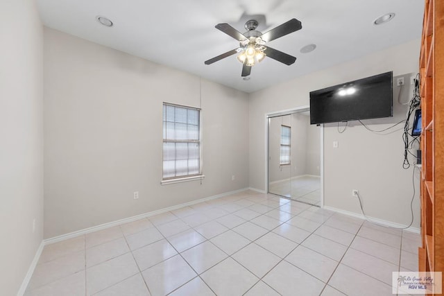 unfurnished bedroom featuring multiple windows, ceiling fan, a closet, and light tile patterned floors