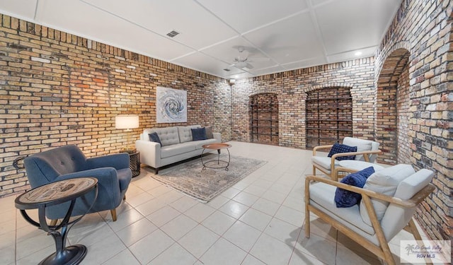 interior space featuring ceiling fan, tile patterned flooring, and brick wall