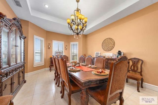 dining room featuring a tray ceiling, light tile patterned floors, and a chandelier