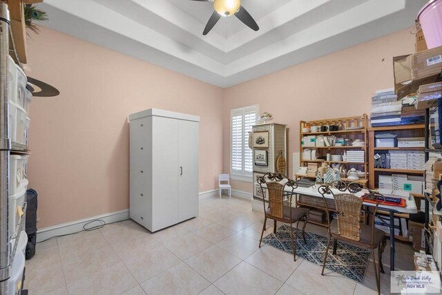 tiled home office featuring ceiling fan and a raised ceiling