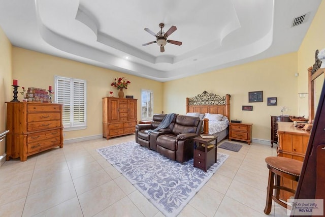 bedroom featuring light tile patterned floors, a tray ceiling, and ceiling fan