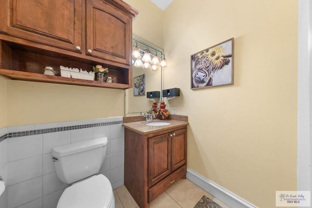 bathroom featuring toilet, vanity, tile patterned floors, and tile walls