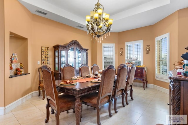 tiled dining room featuring a raised ceiling and a chandelier