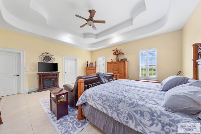 bedroom featuring light tile patterned floors, a tray ceiling, and ceiling fan