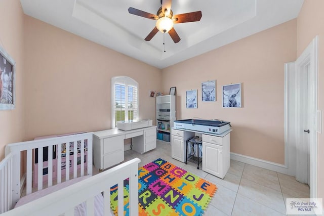 tiled bedroom with ceiling fan and a raised ceiling