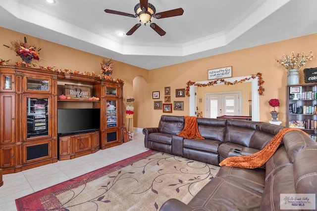 tiled living room with ceiling fan, french doors, and a tray ceiling