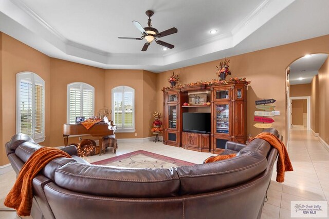 tiled living room with ceiling fan, crown molding, and a tray ceiling