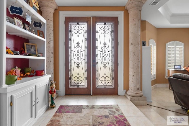 foyer entrance with light tile patterned flooring, decorative columns, and french doors