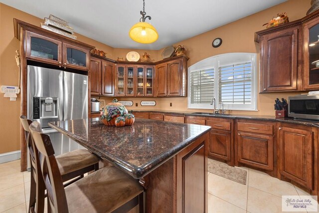 kitchen featuring pendant lighting, light tile patterned flooring, sink, a kitchen island, and a kitchen bar