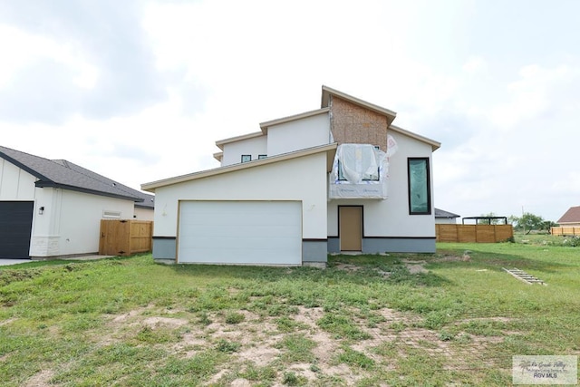rear view of property featuring a yard, a garage, and fence