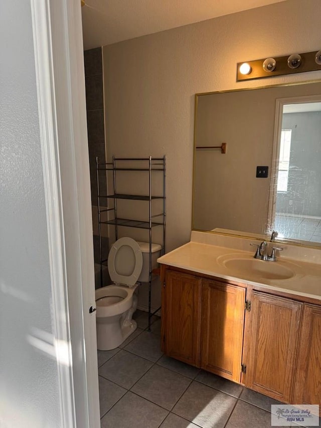 bathroom with toilet, tile patterned flooring, and vanity