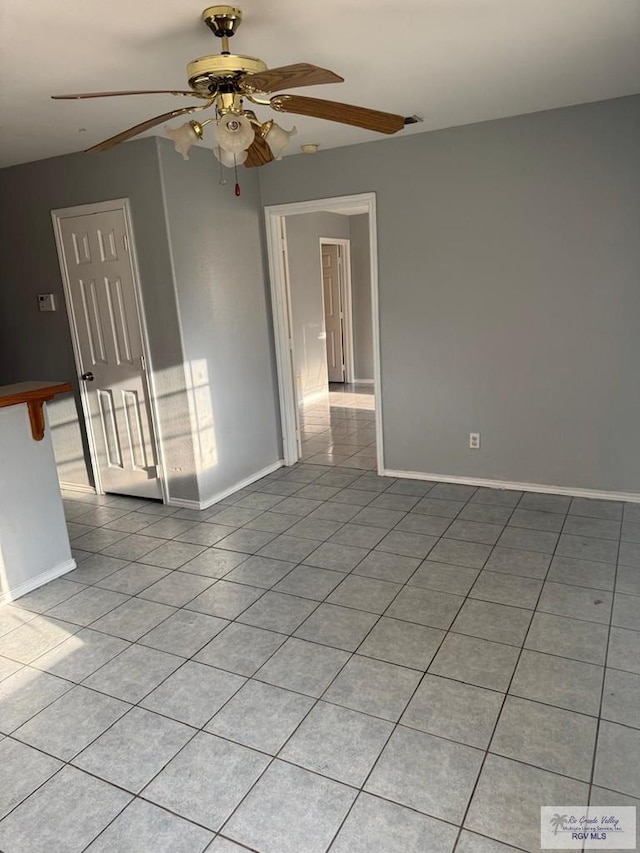spare room with baseboards, ceiling fan, and light tile patterned floors