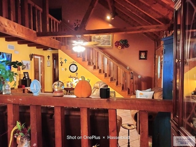 staircase with tile patterned floors and vaulted ceiling with beams