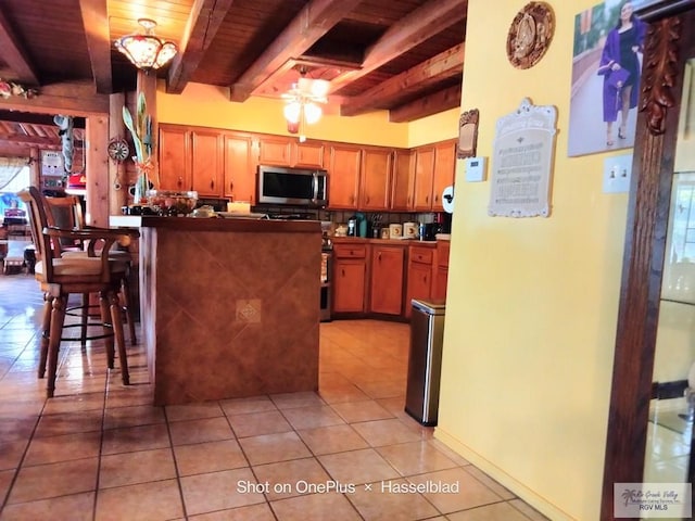 kitchen featuring kitchen peninsula, wood ceiling, ceiling fan, light tile patterned floors, and beamed ceiling