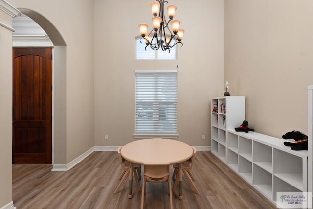 dining space with light hardwood / wood-style floors and an inviting chandelier