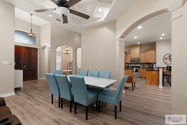 dining space featuring coffered ceiling, ceiling fan with notable chandelier, a towering ceiling, and light hardwood / wood-style flooring