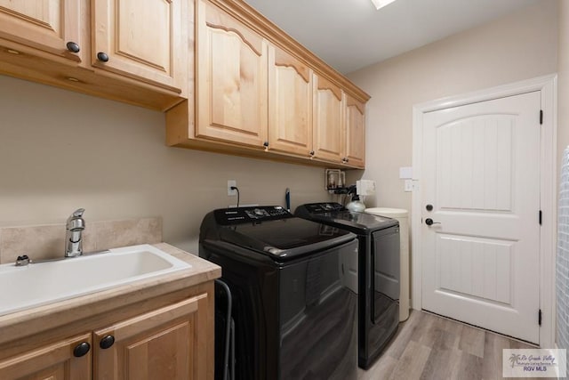 laundry room featuring cabinets, light wood-type flooring, separate washer and dryer, and sink