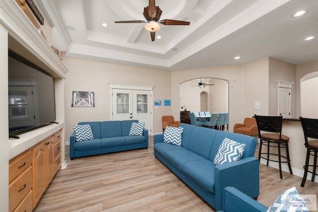 living room featuring ceiling fan, light hardwood / wood-style floors, and a raised ceiling