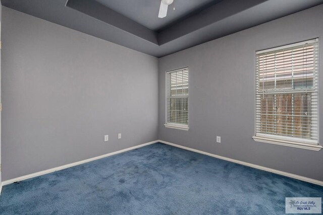 carpeted empty room featuring baseboards, ceiling fan, and a tray ceiling