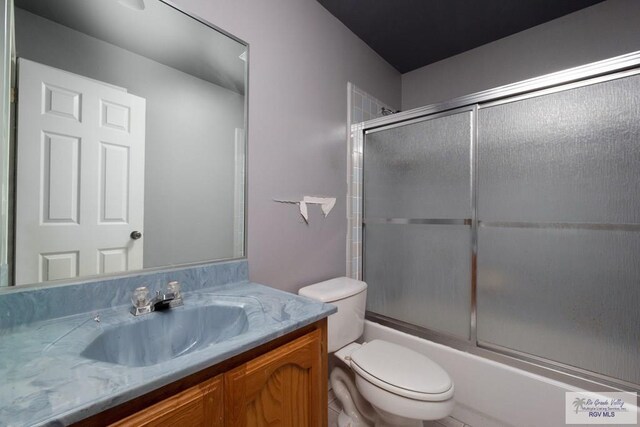 bathroom with vanity, combined bath / shower with glass door, and toilet