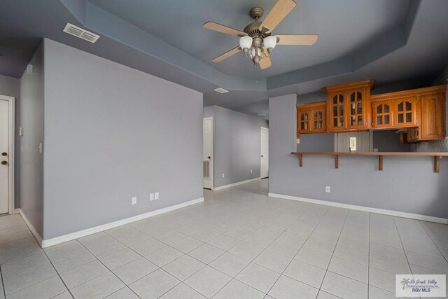 unfurnished living room featuring visible vents, a raised ceiling, ceiling fan, and light tile patterned flooring