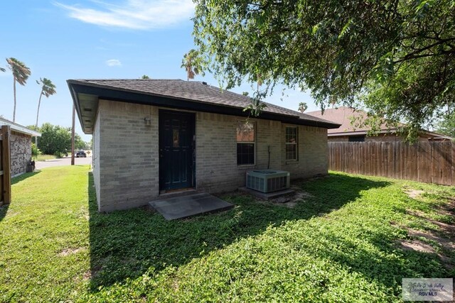 back of property featuring fence, a yard, brick siding, and cooling unit