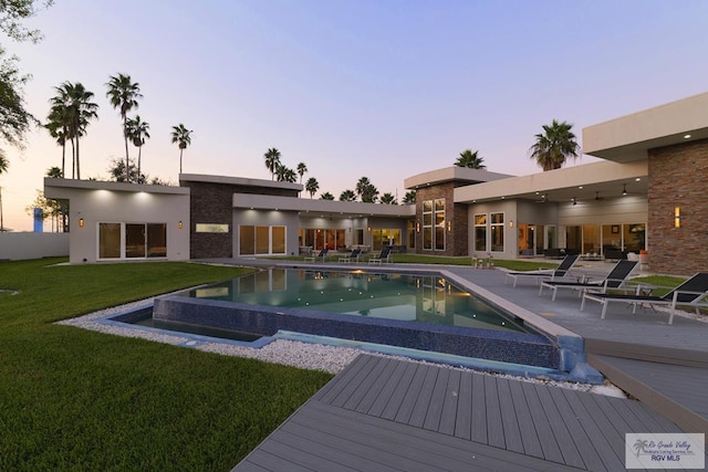 pool at dusk featuring a lawn