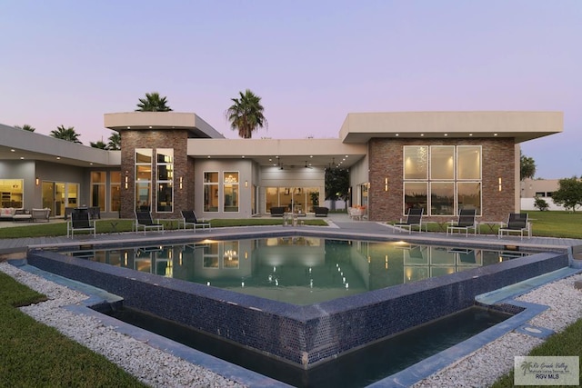 pool at dusk featuring a patio area