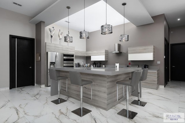 kitchen with a high ceiling, hanging light fixtures, appliances with stainless steel finishes, a kitchen island, and a breakfast bar area