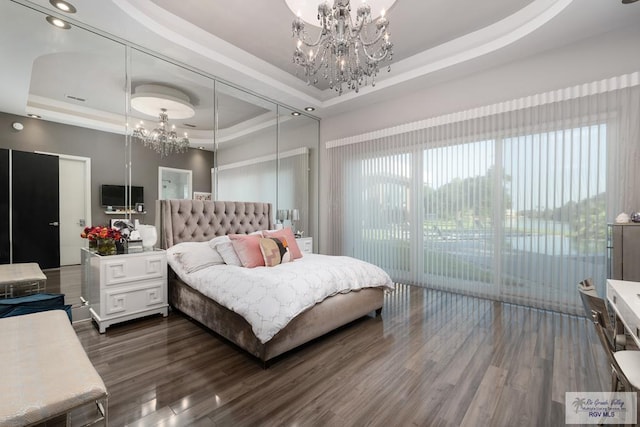 bedroom with a tray ceiling, an inviting chandelier, dark hardwood / wood-style floors, and access to outside