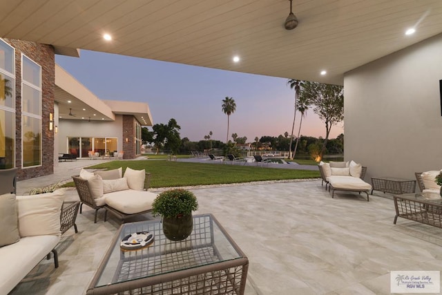 patio terrace at dusk with outdoor lounge area and a lawn