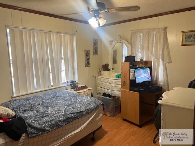 bedroom featuring ceiling fan, light wood-type flooring, and ornamental molding